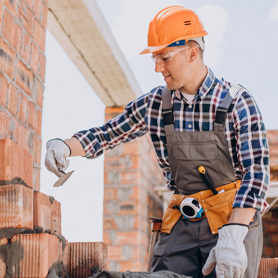 Mason laying brick wall at construction site
