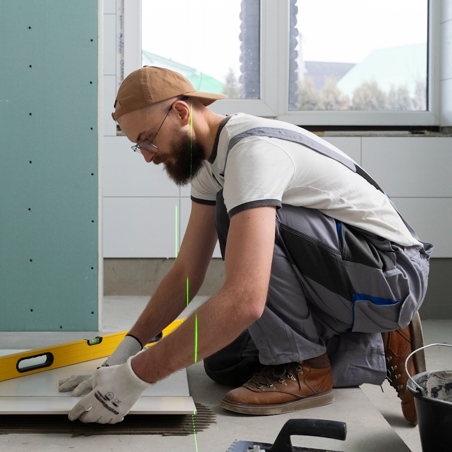 Tile installer laying floor tiles with level tool